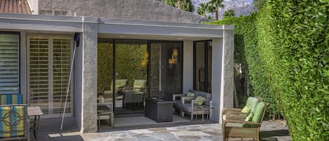 A modern outdoor patio with a pool, seating area, and mountain views.