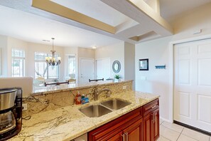 A kitchen with a granite countertop, double sink, and a coffee maker. - 2nd-floor condo with sunset, mtn, & valley views, hot tub, pool, gym, balcony (Oro Valley)