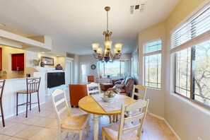 A spacious kitchen with a dining area, a chandelier, and large windows. - 2nd-floor condo with sunset, mtn, & valley views, hot tub, pool, gym, balcony (Oro Valley)