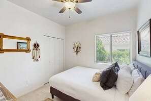 A bedroom with a bed, a ceiling fan, a window with blinds, and wall decorations. - Dog-Friendly Oro Valley Retreat | Private Hot Tub, Catalina Views & Shaded Patio (Oro Valley)