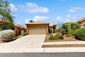A residential property with a garage, a driveway, and a garden with various plants and cacti. - Dog-Friendly Oro Valley Retreat | Private Hot Tub, Catalina Views & Shaded Patio (Oro Valley)