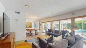 Una sala de estar moderna con un sofá grande, una mesa de centro de madera y un televisor de pantalla plana.
