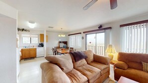 A living room with a sofa, a dining table, and a kitchen in the background.