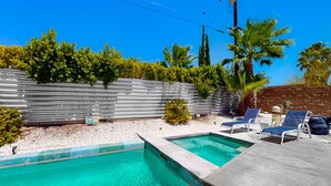 A swimming pool with clear water, surrounded by a stone wall and palm trees. - Elegant Wexler home with private outdoor pool & spa - 2 dogs welcome (Palm Springs)