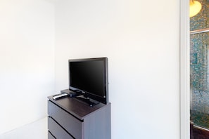 Ein Flachbildfernseher steht auf einer Holzkommode vor einer weißen Wand.