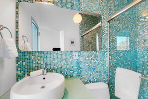 Ein Badezimmer mit einem weißen Waschbecken, einem Spiegel und einer Dusche.