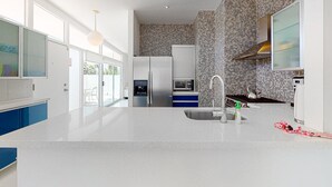 A modern kitchen with a white countertop, stainless steel appliances, and a patterned backsplash. - Elegant Wexler home with private outdoor pool & spa - 2 dogs welcome (Palm Springs)