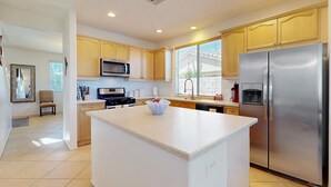 Una cocina moderna con una isla central, electrodomésticos de acero inoxidable y armarios de madera clara.