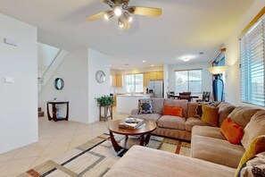 A spacious living room with a sofa set, a coffee table, and a ceiling fan. - Beautiful house with private pool, pool table and outdoor firepit (Indio)