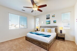 A bedroom with a bed, a ceiling fan, a nightstand, and a window with blinds. - Beautiful house with private pool, pool table and outdoor firepit (Indio)