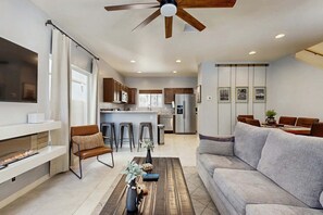 A modern living room with a fireplace, a sofa, a coffee table, and a TV mounted on the wall.