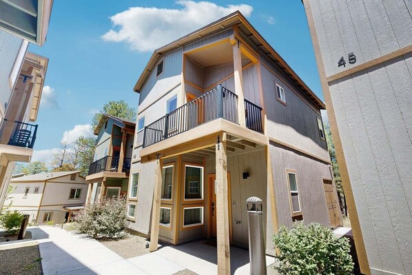 A multi-story residential building with balconies, a covered entryway, and a visible door.