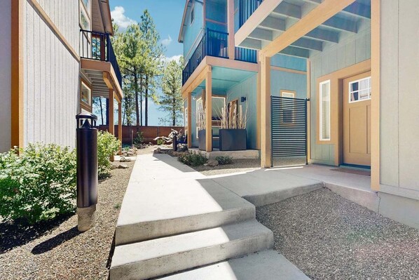 A modern building with a concrete pathway leading to a door, surrounded by gravel and small plants.