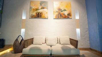 A room with a sofa, two paintings on the wall, and a window.