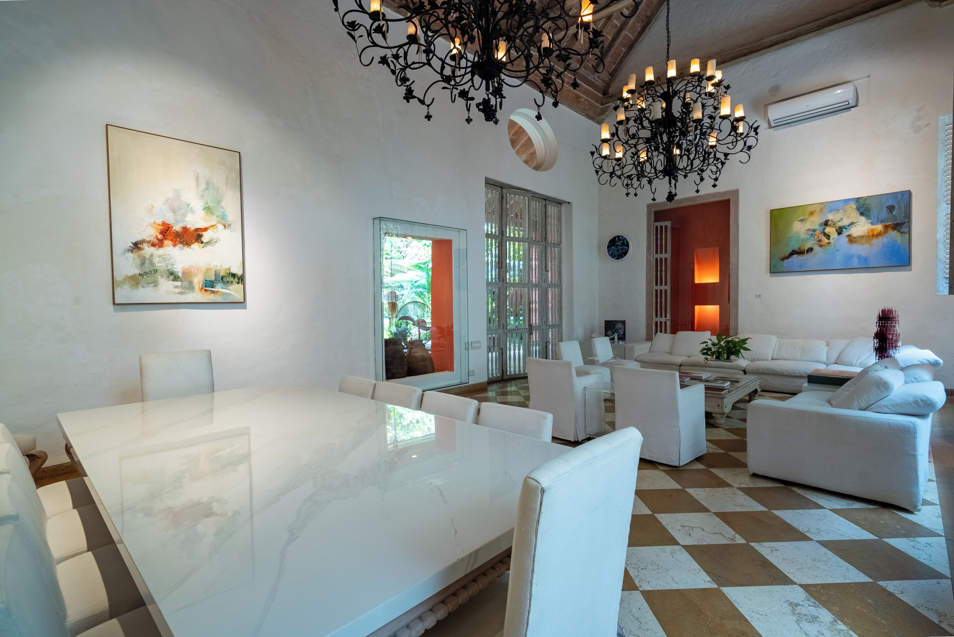 A modern living room with a marble table, white sofas, and a chandelier.