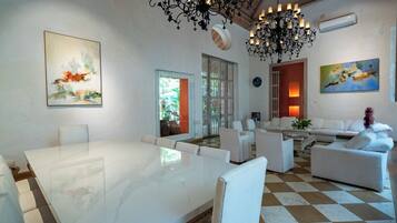 A modern living room with a marble table, white sofas, and a chandelier.