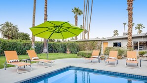 A pool area with lounge chairs and a green umbrella. - Mid-century modern home with private pool, spa, grill & mountain views (Palm Springs)