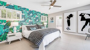 A bedroom with a bed, nightstand, and wall art. - Mid-century modern home with private pool, spa, grill & mountain views (Palm Springs)