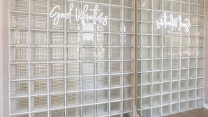 A wall with a grid of clear plastic panels and two illuminated signs reading "Good Vibrations." - Mid-century modern home with private pool, spa, grill & mountain views (Palm Springs)