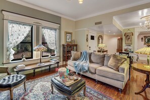 A cozy living room with a sofa, ottoman, and a coffee table with snacks. - Dog-friendly charming historic home with patio, central AC, & washer/dryer (Tucson)