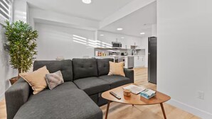 Una sala de estar moderna con un sofá seccional gris, una mesita de madera y una planta en maceta.