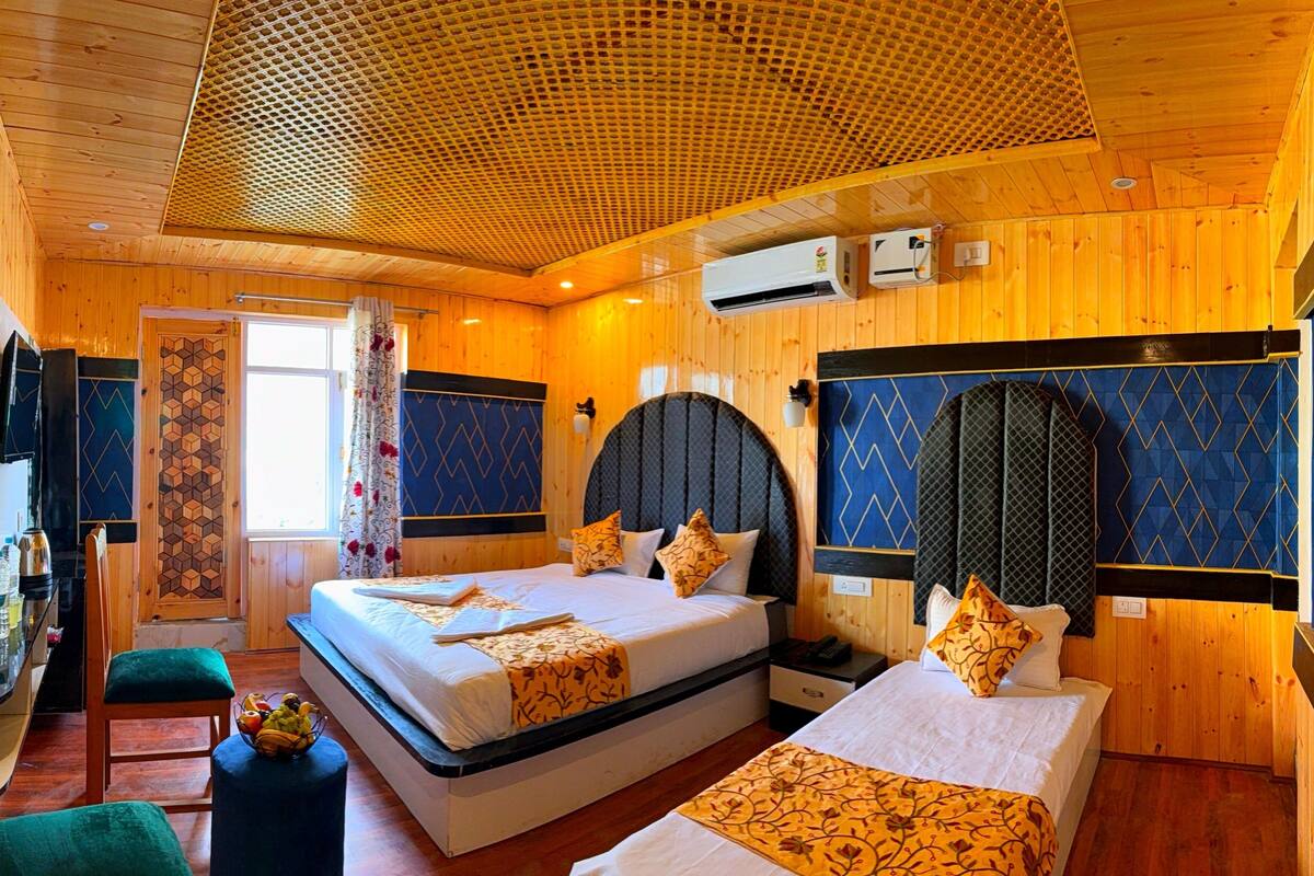 A wooden cabin-style room with two beds, a small kitchenette, and a ceiling with a honeycomb pattern.
