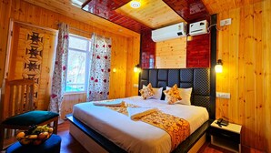 A wooden room with a bed, a window, curtains, an air conditioner, and a bedside table. - Poets inn (Pahalgam)