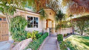 A residential house with a front yard, a garage, and a gated entrance. - Beautiful home with private pool, outdoor kitchen & enclosed yard (Indio)