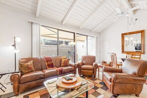 A spacious living room with a brown leather sofa, a glass coffee table, and a brown leather armchair. - Light & bright getaway w/ private gas grill, shared pool, pool spa, & tennis (Palm Springs)