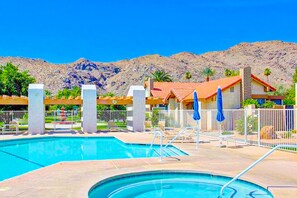 A swimming pool with a mountain backdrop, a fenced area with lounge chairs, and a building with a red roof. - Light & bright getaway w/ private gas grill, shared pool, pool spa, & tennis (Palm Springs)