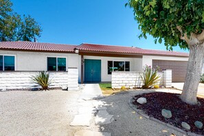 Ein zweistöckiges Haus mit rotem Ziegeldach, blauer Haustür und Garage.