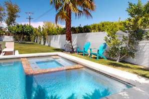 A swimming pool with a tiled edge, surrounded by a grassy area and a white fence. - Newly-remodeled, family & dog-friendly house w/private pool spa & outdoor pool (Palm Springs)