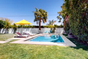 Ein Pool mit Liegestühlen und einem gelben Sonnenschirm.