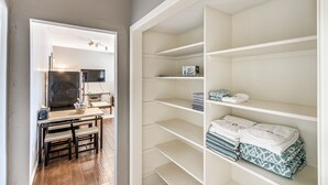 Una habitación moderna con una mesa de comedor de madera, un televisor de pantalla plana y una estantería empotrada con toallas dobladas.