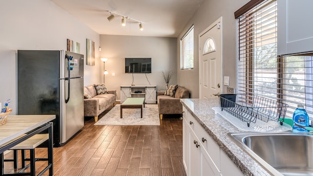 Una cocina moderna con refrigerador integrado, una mesa de comedor y un área de estar con sofá y mesa de centro.