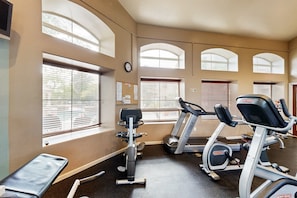 Une salle de sport équipée de tapis de course, de vélos elliptiques et d’un banc de musculation.