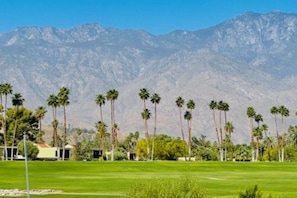A golf course with a mountain backdrop, palm trees, and a small building. - Inviting townhouse w/mtn. views,  community pools & spas-close to golf & hiking (Palm Springs)