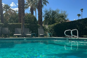A swimming pool with clear blue water, surrounded by palm trees and lounge chairs. - Inviting townhouse w/mtn. views,  community pools & spas-close to golf & hiking (Palm Springs)