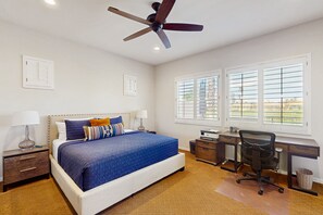 Ein Schlafzimmer mit Bett, Schreibtisch, Stuhl und Deckenventilator.