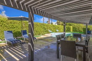An outdoor patio area with a pergola, lounge chairs, a dining table, and a pool. - Marvelous, Dog/Family-Friendly House w/Private Grill, Outdoor Pool, Attached Spa (Palm Springs)
