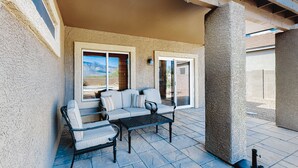 A covered patio area with a sofa, chairs, and a table. - Captivating desert home with private pool, game room, grill, backyard & W/D (Tucson)