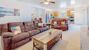 A living room with two brown sofas, a wooden coffee table, and a ceiling fan. - Captivating desert home with private pool, game room, grill, backyard & W/D (Tucson)