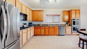 A modern kitchen with wooden cabinets, stainless steel appliances, and a granite countertop. - Captivating desert home with private pool, game room, grill, backyard & W/D (Tucson)