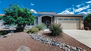 A house with a garage, a driveway, and a landscaped garden with rocks and plants. - Captivating desert home with private pool, game room, grill, backyard & W/D (Tucson)