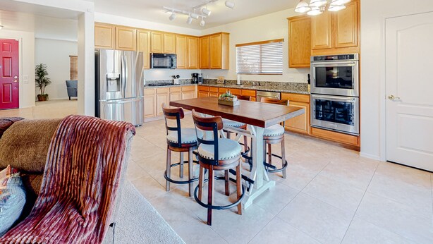 A modern kitchen with wooden cabinets, stainless steel appliances, and a central island with bar stools. - Captivating desert home with private pool, game room, grill, backyard & W/D (Tucson)
