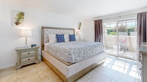 A bedroom with a large bed, a nightstand, a window with curtains, and a view of the outdoors. - Gated resort condo with outdoor pool, hot tub, & tennis - walk to dining (Palm Springs)