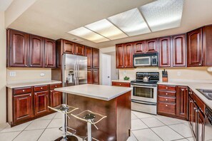 A modern kitchen with wooden cabinets, stainless steel appliances, and a central island. - Pleasant home with private pool, spa & private gas grill - close to downtown (Palm Springs)