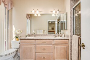A bathroom with a beige countertop, two sinks, a mirror, and a toilet. - Pleasant home with private pool, spa & private gas grill - close to downtown (Palm Springs)