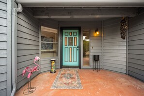A front porch with a turquoise door, a patterned rug, a pink flamingo sculpture, and a hanging plant. - Ground-floor mountain-view home with patio, central AC & washer/dryer (Sedona)