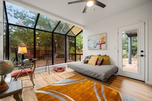 A modern bedroom with a large window, a bed, a desk with a globe, and a colorful ottoman. - Ground-floor mountain-view home with patio, central AC & washer/dryer (Sedona)
